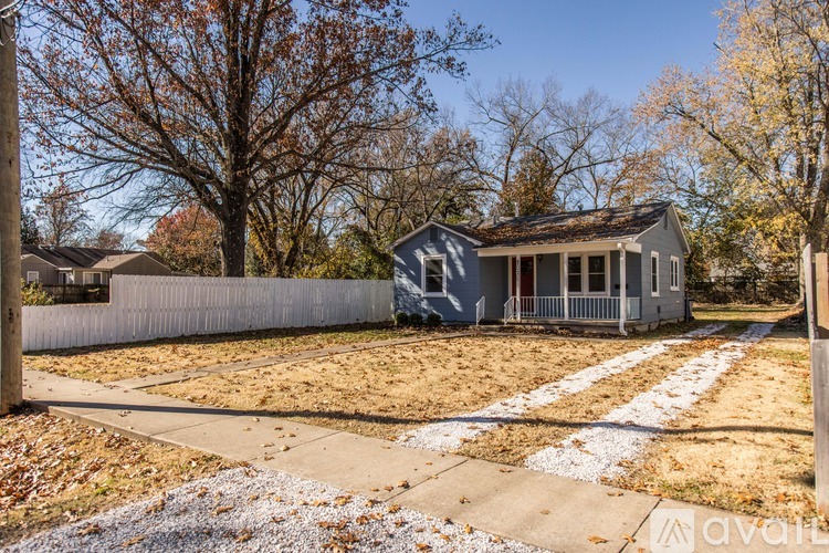 A house with a grey front yard and a white fence.