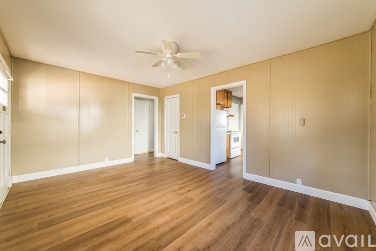 A spacious room with wooden flooring and a ceiling fan.