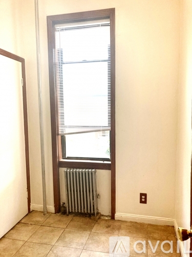 A room with a window and a radiator on the floor.