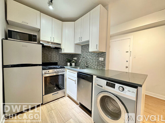 A kitchen with a refrigerator, oven, and washing machine.