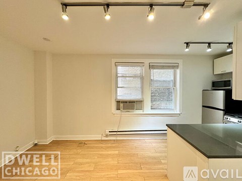 A kitchen with a black counter top and wooden flooring.