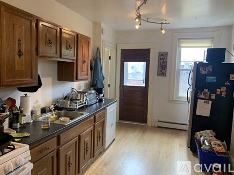 A kitchen with wooden cabinets and a black fridge.