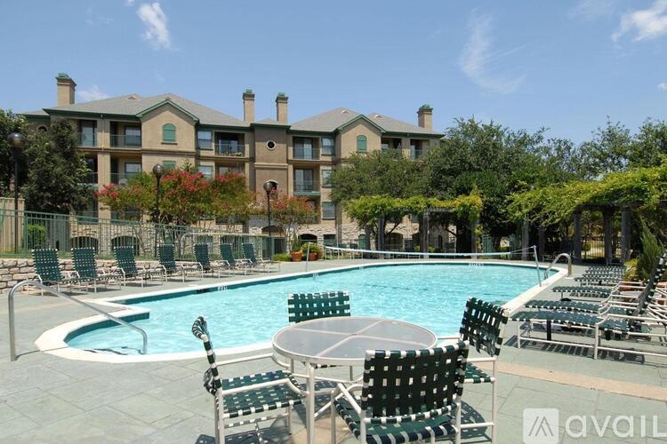 A pool area with chairs and a building in the background.
