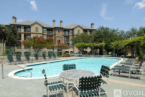 A pool area with chairs and a building in the background.