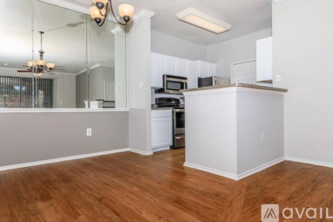 A kitchen with white cabinets and a wooden floor.