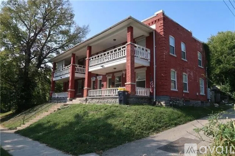 A red two-story house with a balcony on the second floor.