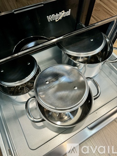 A Whirlpool stove top with three pots on it.