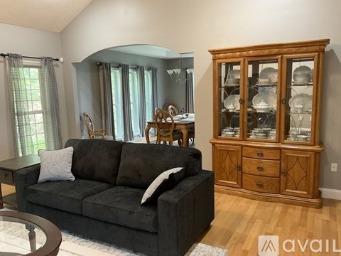 A living room with a grey couch and wooden furniture.