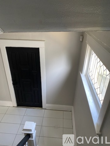A room with a white floor and a black door.