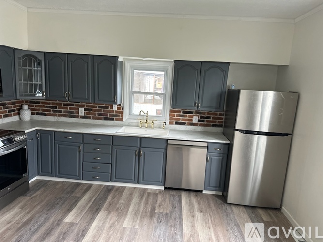 A kitchen with dark grey cabinets and a stainless steel refrigerator.