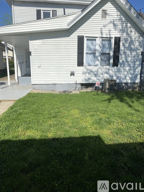 A house with a white siding and a grey roof with a green lawn in front.