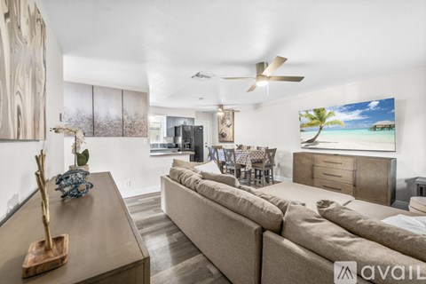 A living room with a beige sofa and a painting of a beach scene on the wall.