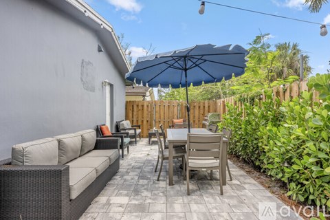 A patio with a table and chairs under a blue umbrella.