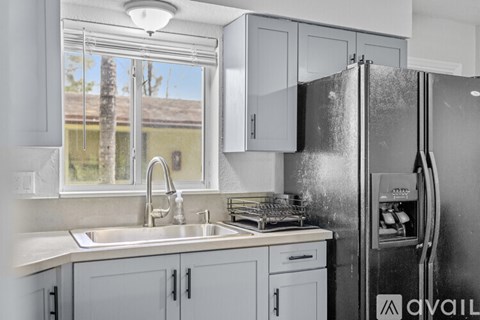 A kitchen with a black stove top oven and grey cabinets.