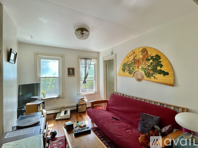 A living room with a red couch and a large circular painting on the wall.