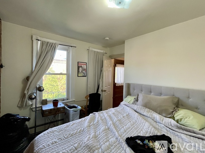 A bedroom with a large bed and a window with curtains.