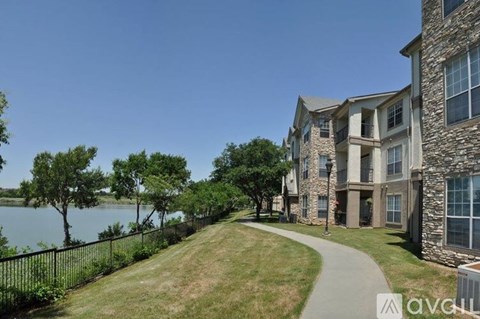A modern apartment building with a walkway and a body of water in the background.