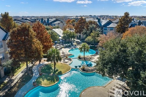 A bird's eye view of a pool surrounded by trees and houses.