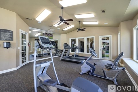 A gym with treadmills, elliptical machines, and a fan.
