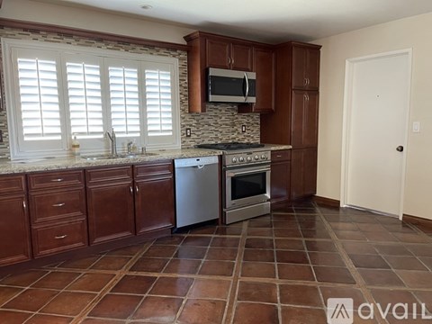A kitchen with brown cabinets and a stone backsplash.
