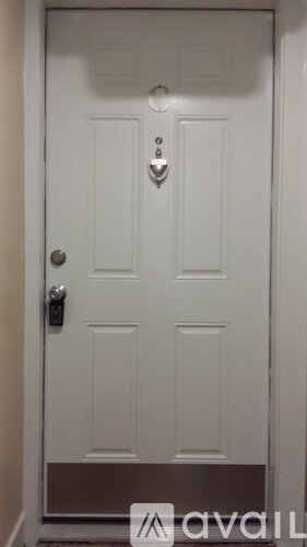 A white door with a silver handle and a small decorative piece above the handle.