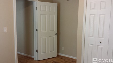A white door is open in a room with wood flooring.