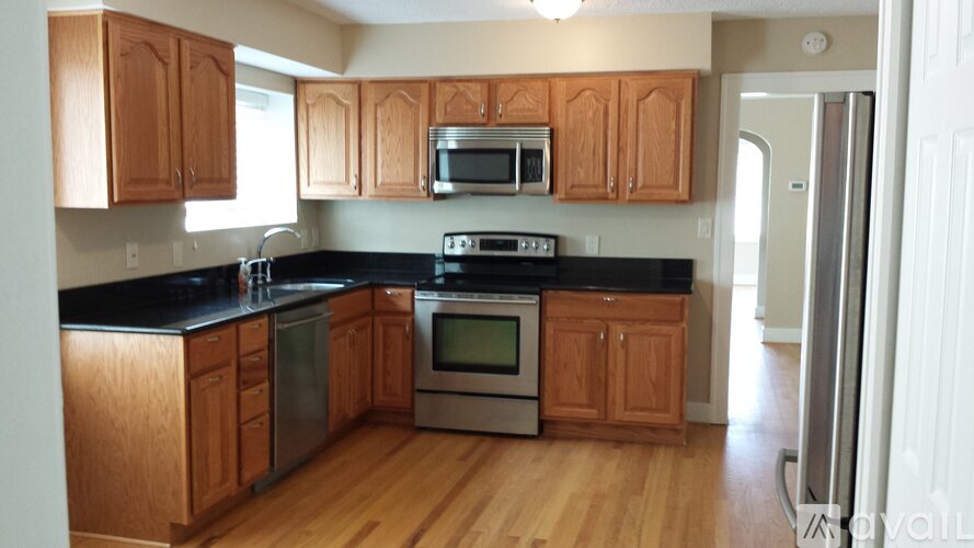 A kitchen with wooden cabinets and black countertops.