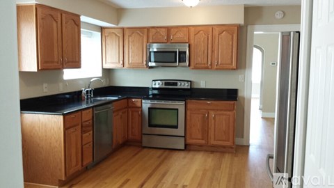 A kitchen with wooden cabinets and black countertops.