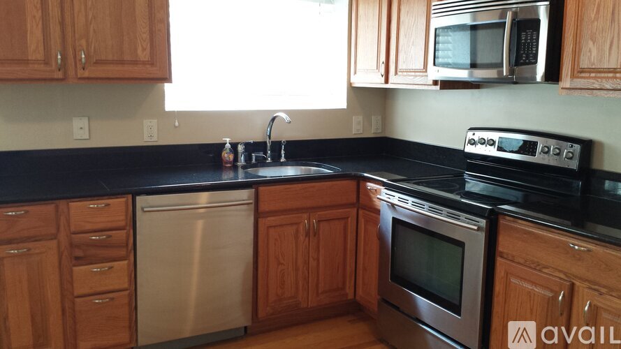A kitchen with wooden cabinets and black countertops.