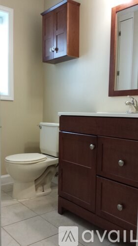 A white toilet sits next to a brown cabinet in a bathroom.