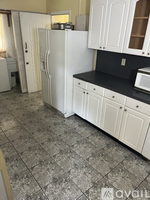 A kitchen with white cabinets and a black countertop.