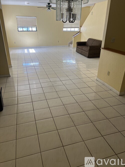 A spacious room with a fan and a brown couch.