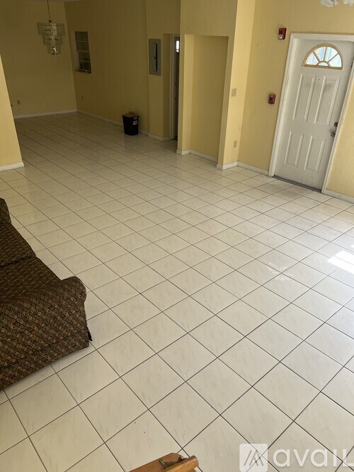 A room with a white tiled floor and a door on the right side.