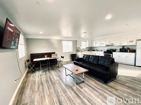 A living room with a black couch and a wooden floor.