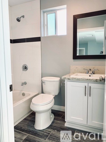 A white toilet sits in a bathroom next to a sink and a bathtub.