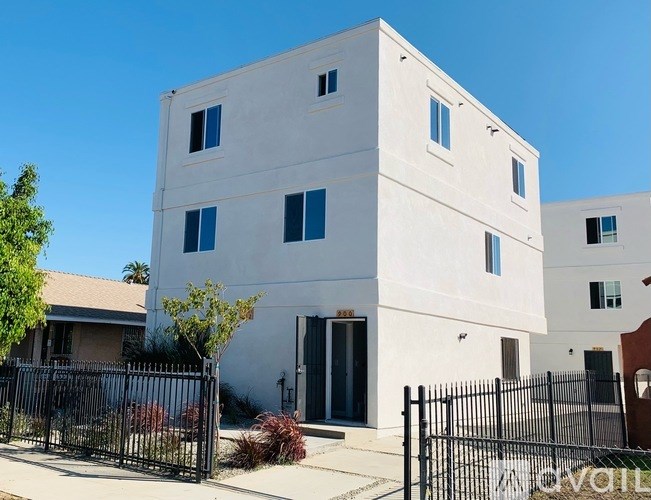 A white two-story building with a black fence in front.