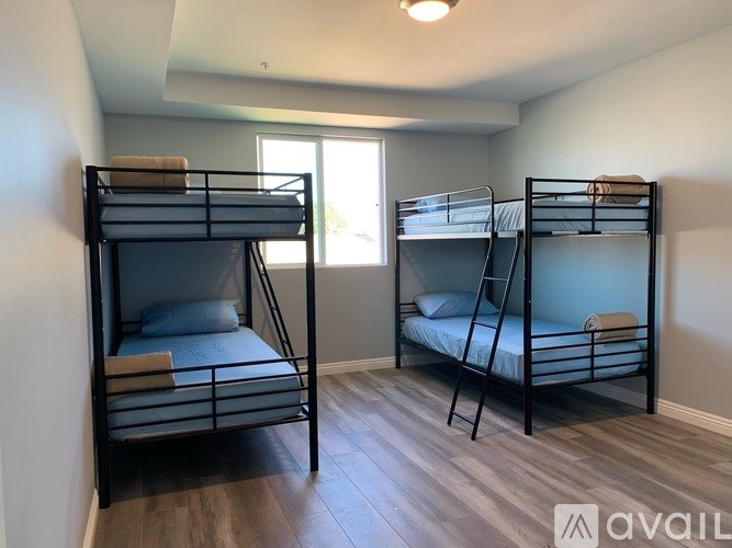 Two bunk beds in a room with wooden floors and white walls.