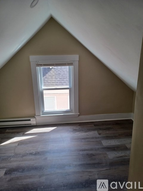 A room with a window and wooden flooring.