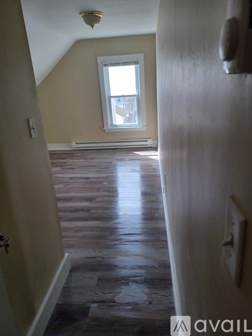 A hallway with wooden floors and a window.