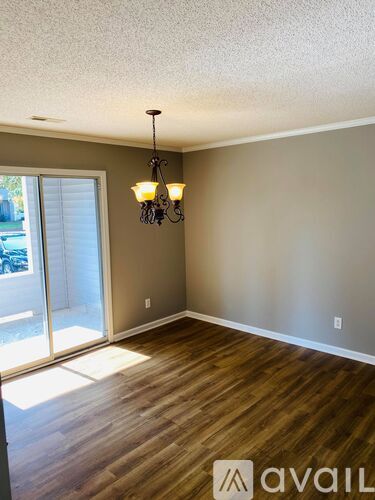 A room with dark wood flooring and a window with blinds.