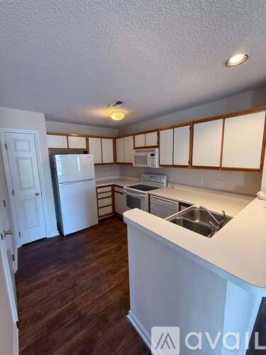 A kitchen with white appliances and wooden cabinets.