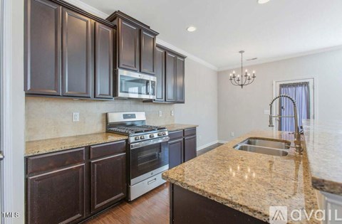 A kitchen with dark brown cabinets and a granite countertop.