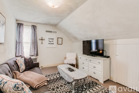 A living room with a grey couch, a white dresser, and a television on top of it.