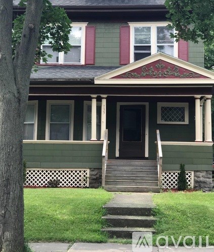 A green house with a red window trim.