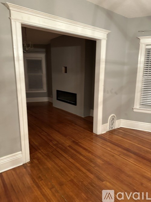 A room with a fireplace and wood flooring.