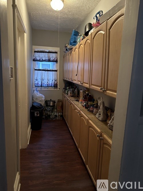 A kitchen with wooden cabinets and a window with curtains.