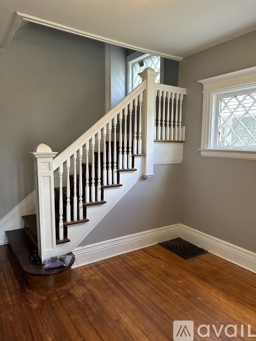 A wooden staircase with white railings and a window with a diamond pattern.