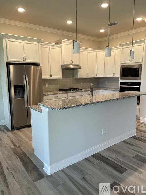A kitchen with white cabinets and a granite countertop.