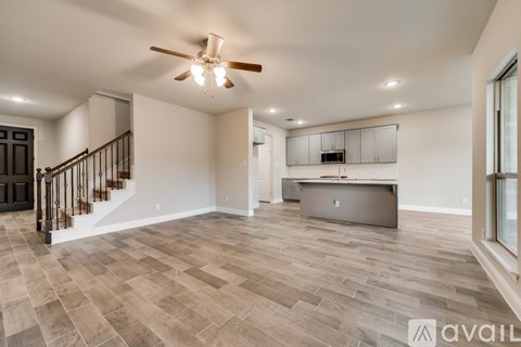 A spacious room with a staircase and a ceiling fan.
