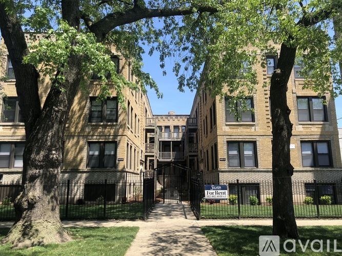 A tree-lined walkway leads to a brick building with a "For Rent" sign.